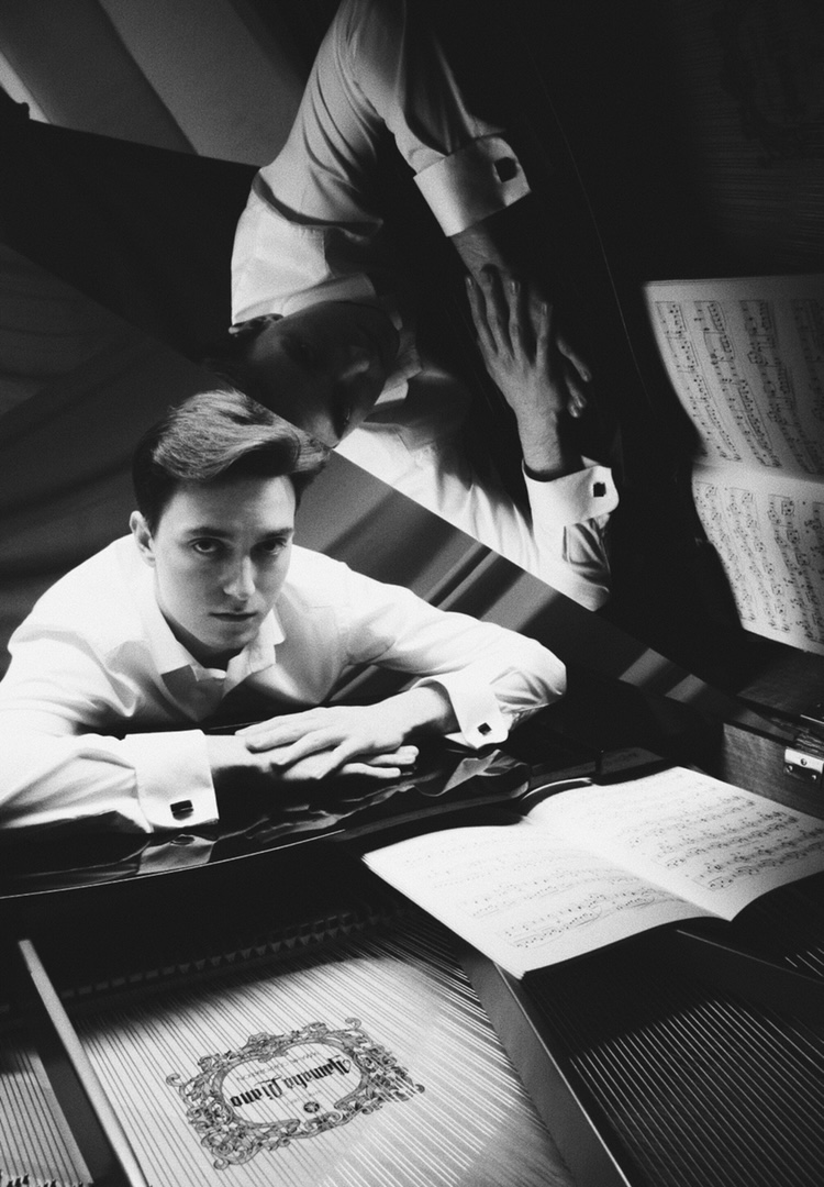Monochromatyczne zdjęcie Eryka Ploplisa przy fortepianie